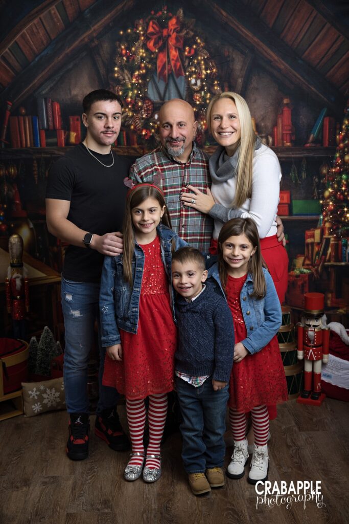 Parents with older teenage son and three younger children standing together for Christmas portraits.
