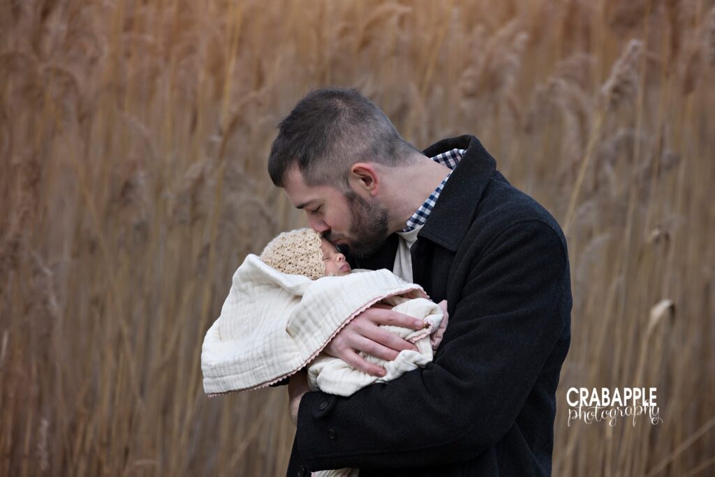 Dad kissing baby’s forehead during outdoor family photo session
