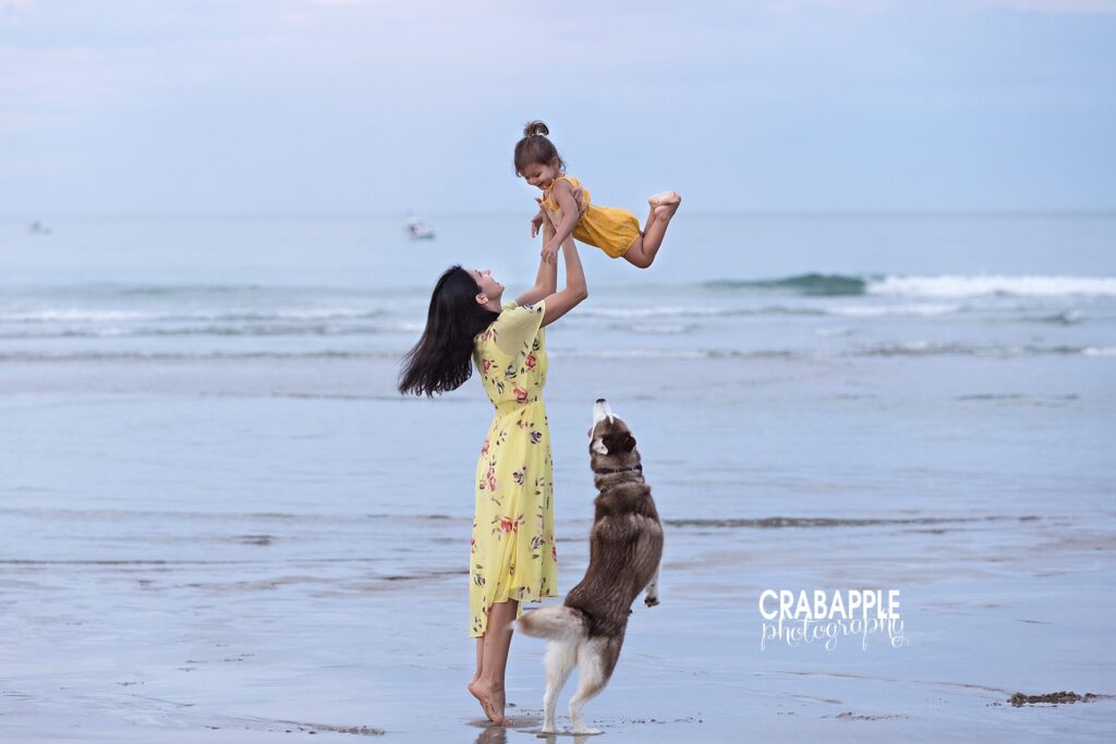 Playful moment between mom and child with pet dog during North Shore beach family session
