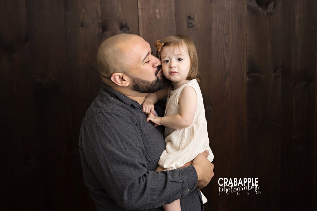 Playful dad and toddler fall photo in cozy indoor studio. Playful indoor fall photo of dad and toddler in rustic studio setting.