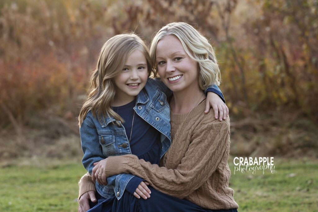 Mom and daughter sharing a hug surrounded by colorful fall leaves
