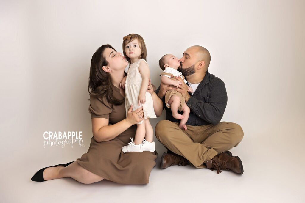 Cozy indoor fall family portraits in natural light studio. Family of four snuggling together during cozy indoor fall studio session with warm natural light.