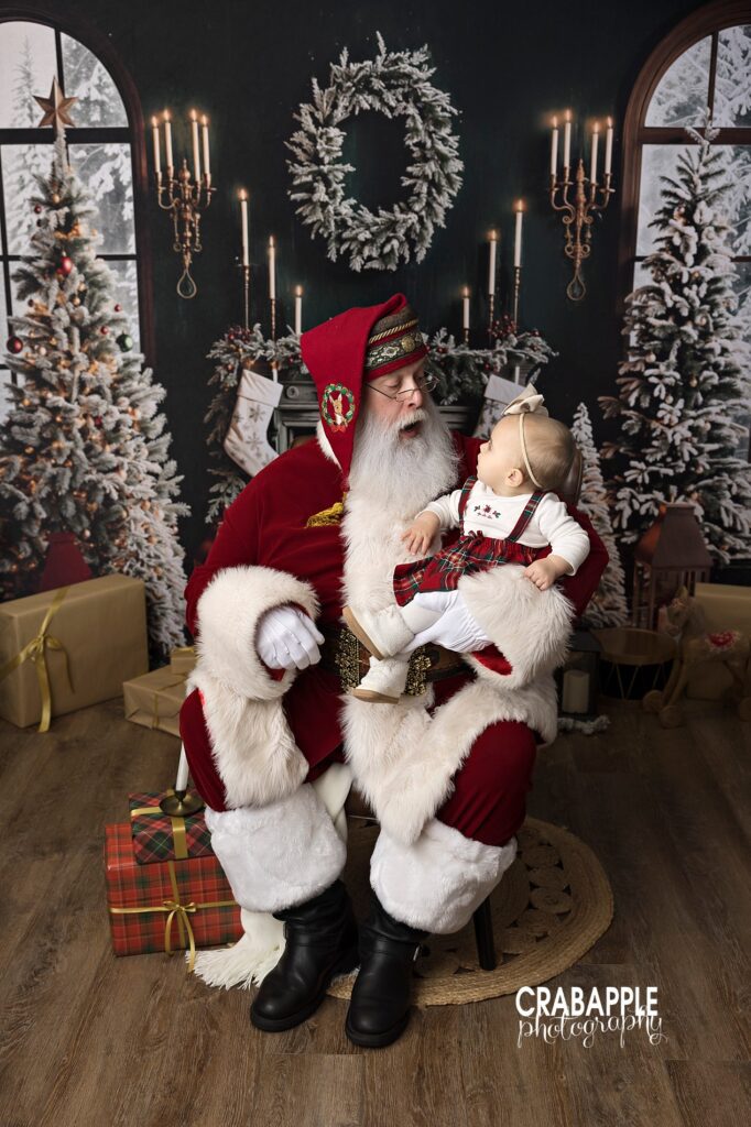 Santa holding baby girl and smiling as they look at each other
