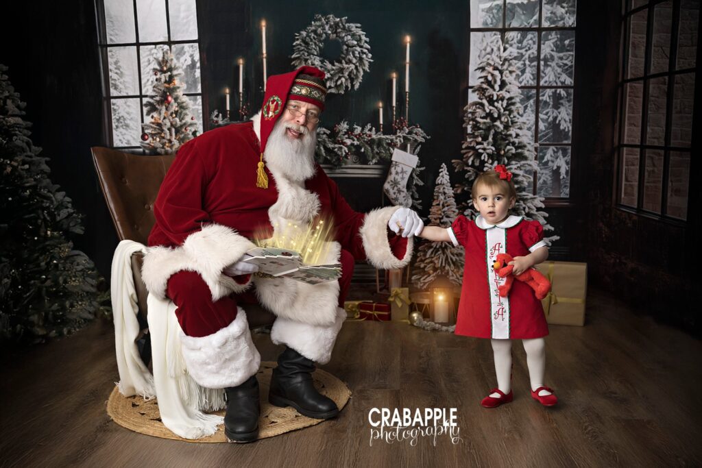 Santa Claus holds hands with a toddler at a studio in Andover MA