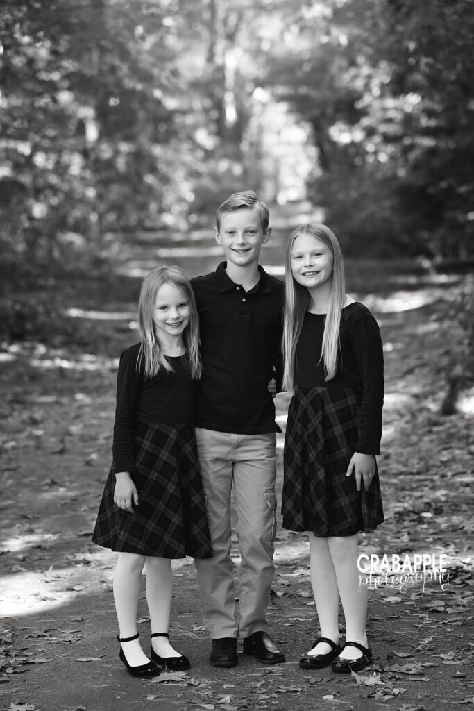 Black and white image of siblings smiling together outdoors.
