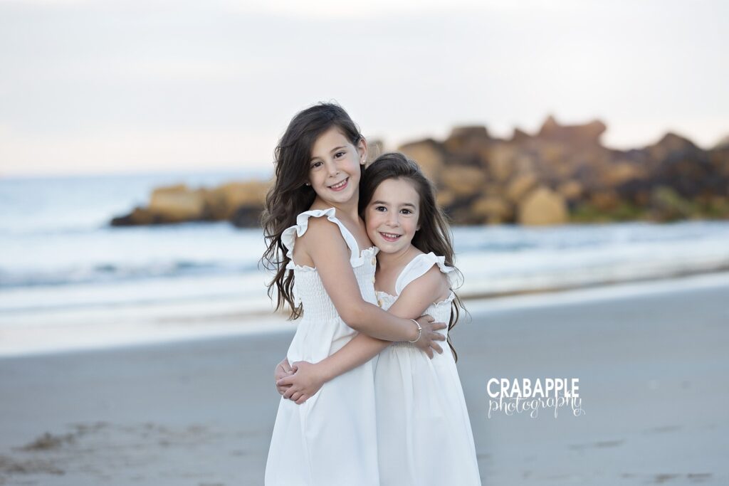 Two sisters hugging by the water during family beach photos

