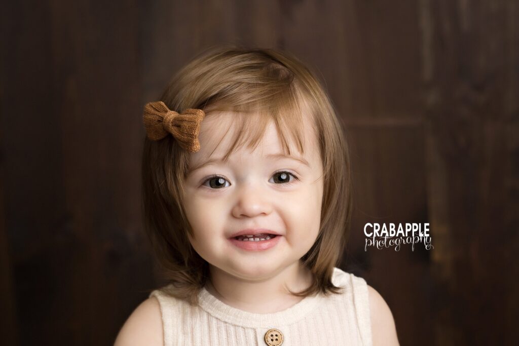 Cozy solo toddler fall portrait in natural light studio. Solo portrait of toddler girl smiling during cozy indoor fall studio session.