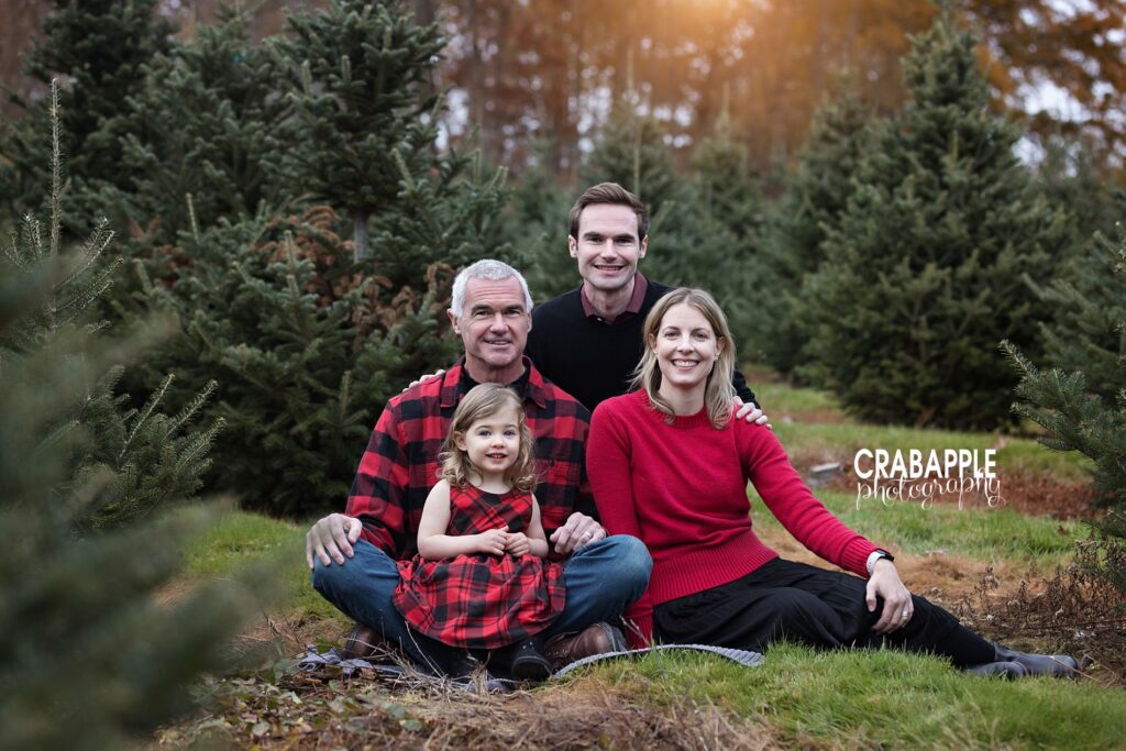 A family in coordinating red and black outfits pose together during family tree farm photos