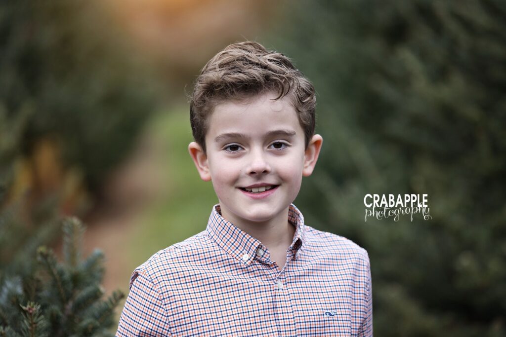 Child smiling during solo holiday portrait at Massachusetts tree farm
