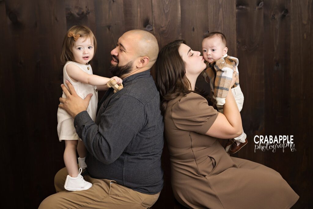 Warm fall family session with parents sitting back to back and each holding a child.