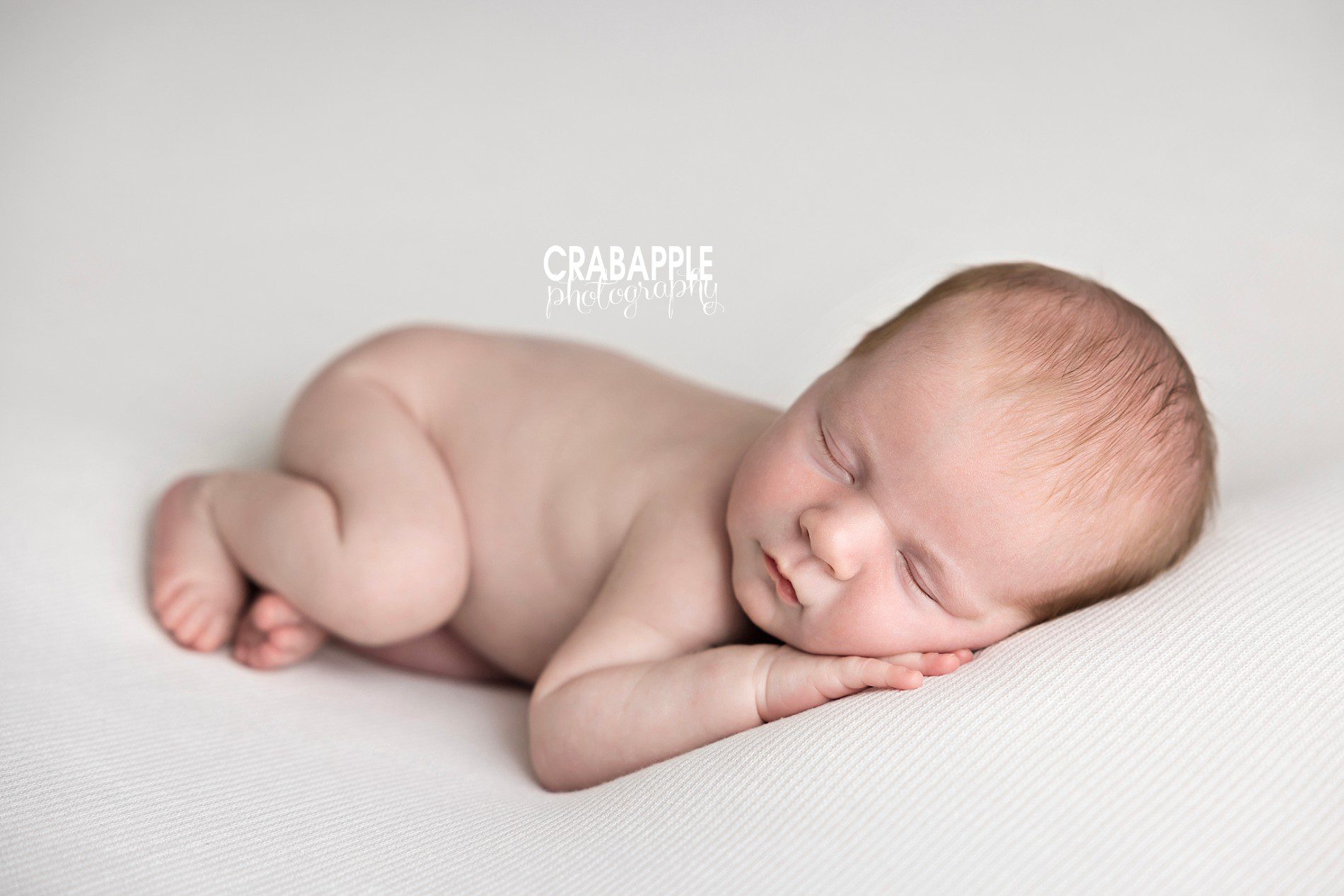 Newborn baby un-swaddled on white blanket sleeping peacefully | North Shore MA newborn photographer
