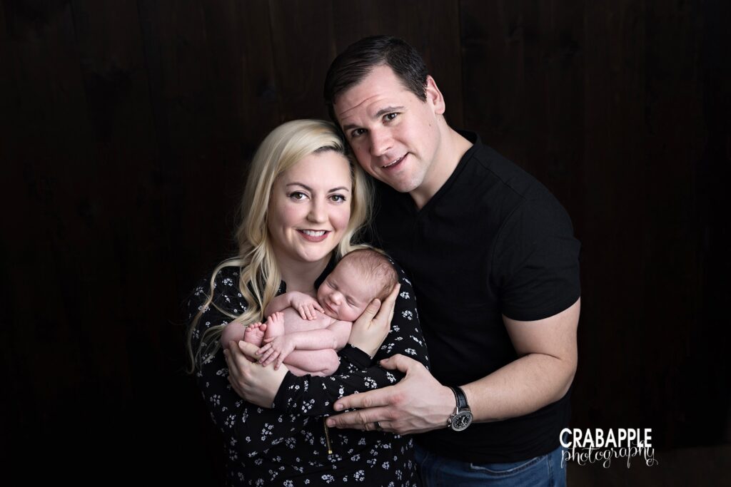 Parents holding newborn baby during family portraits on black backdrop | Andover MA newborn photographer
