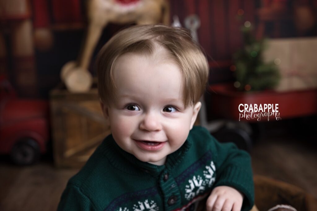 Solo portrait of a 1 year old boy in green sweater during family Christmas photos near Haverhill MA