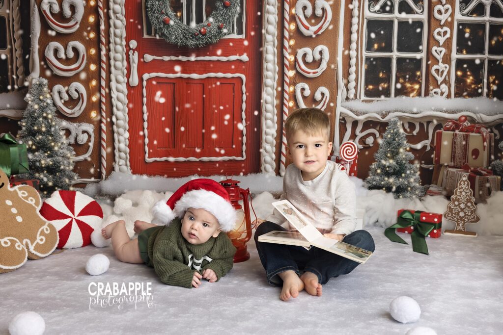 Two brothers  reading together on a gingerbread backdrop during family Christmas photos

