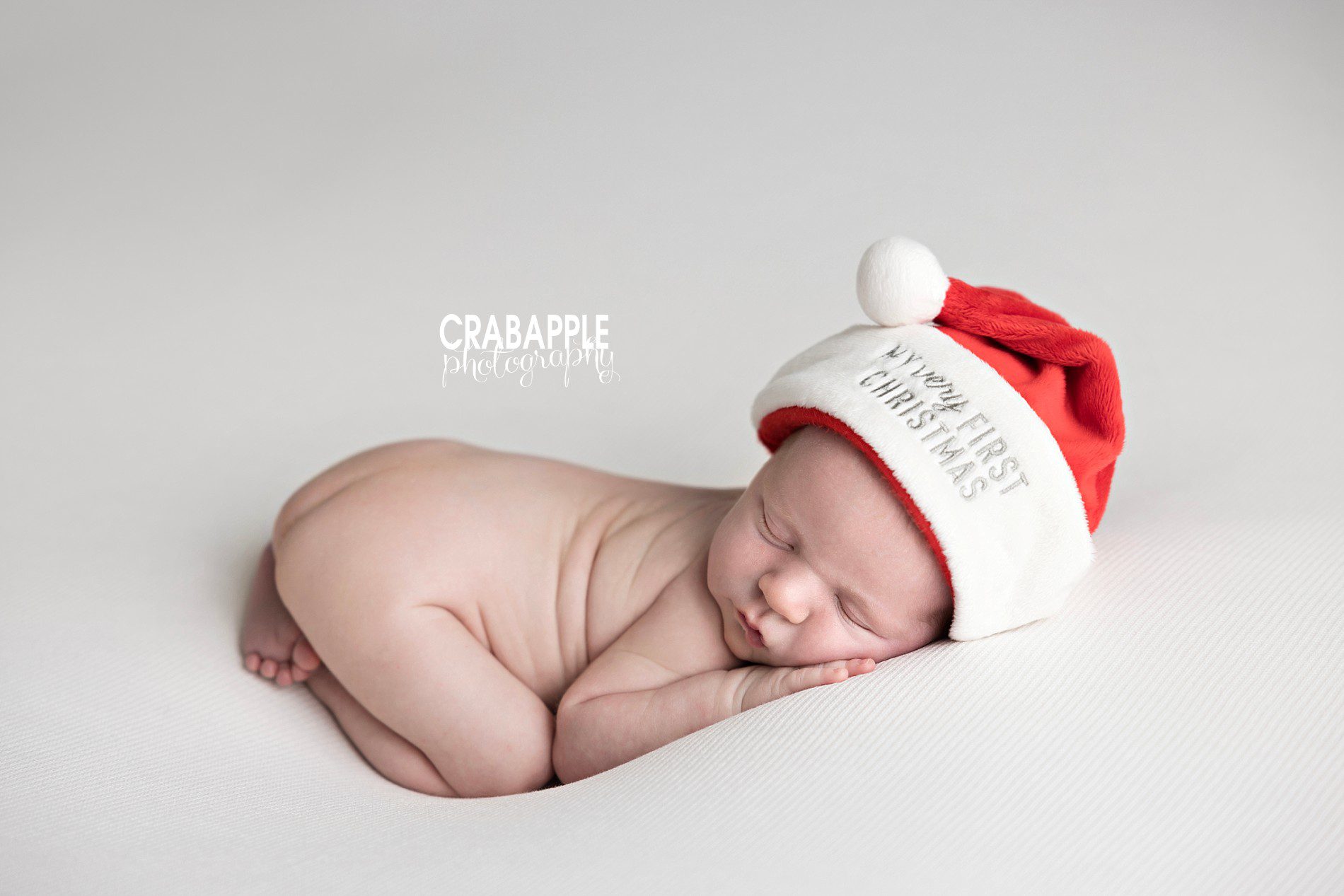 Newborn baby wearing tiny Santa hat on soft blanket | Andover MA newborn Christmas photos
