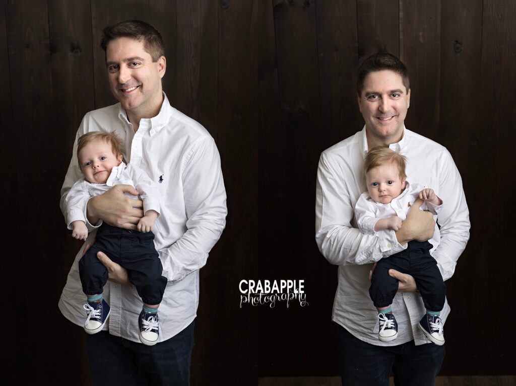 Father holding newborn baby boy with dark rustic wood backdrop during studio portrait session
