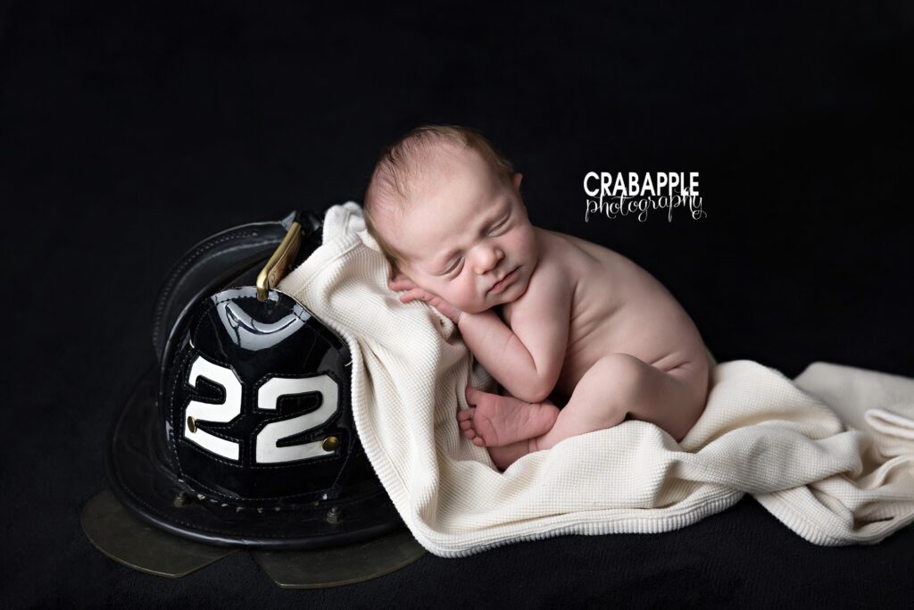 Newborn baby boy posed sleeping beside a firefighter helmet during Andover MA newborn session.
