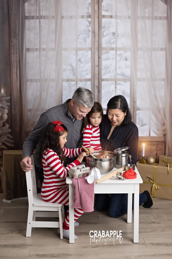 Mom, dad, and two daughters make cookies together in candid photo during Andover MA mini sessions
