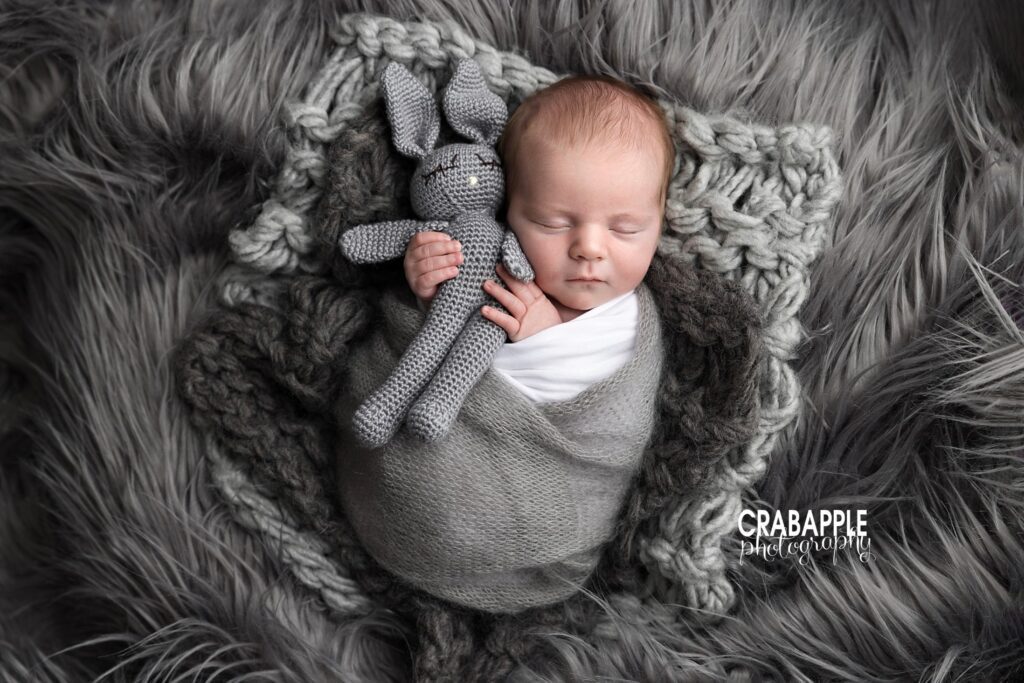 Newborn baby in gray swaddle holding stuffed animal | Studio newborn photography Andover
