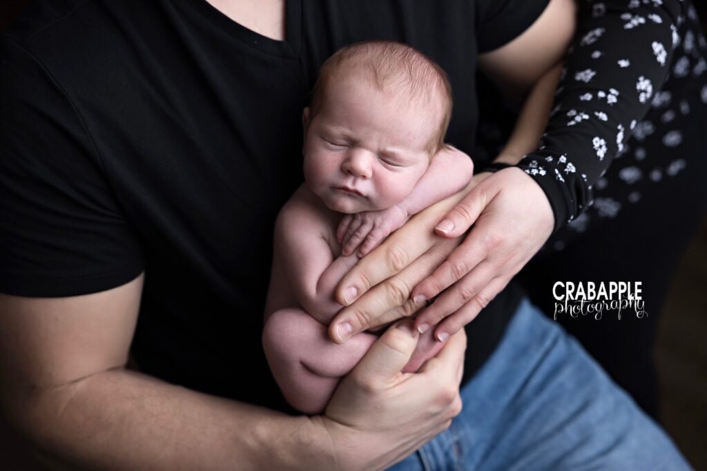 Newborn baby cradled in father’s hands, peaceful and sleepy | Studio newborn photography Andover
