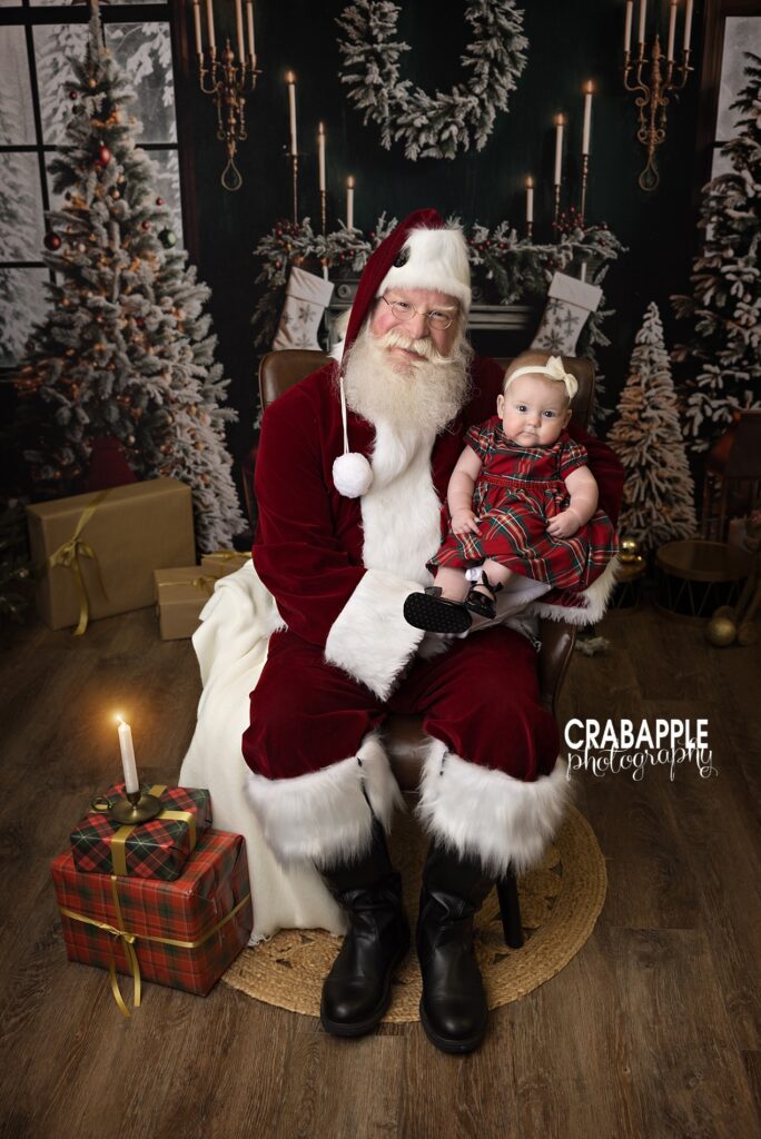 Santa holds a young girl in front of a festive backdrop during private Santa mini sessions north of Boston