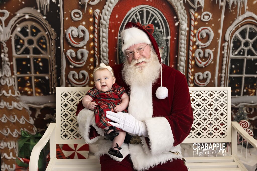 Santa smiles while holding an infant girl during Christmas portraits with Santa north of Boston MA