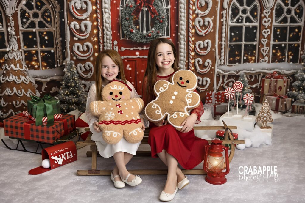 Sisters holding gingerbread stuffed animals during cozy Christmas studio photo session