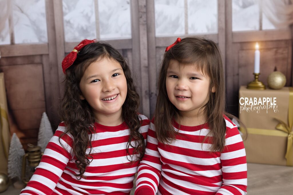 Two sisters in matching red and white striped pajamas for holiday portraits
