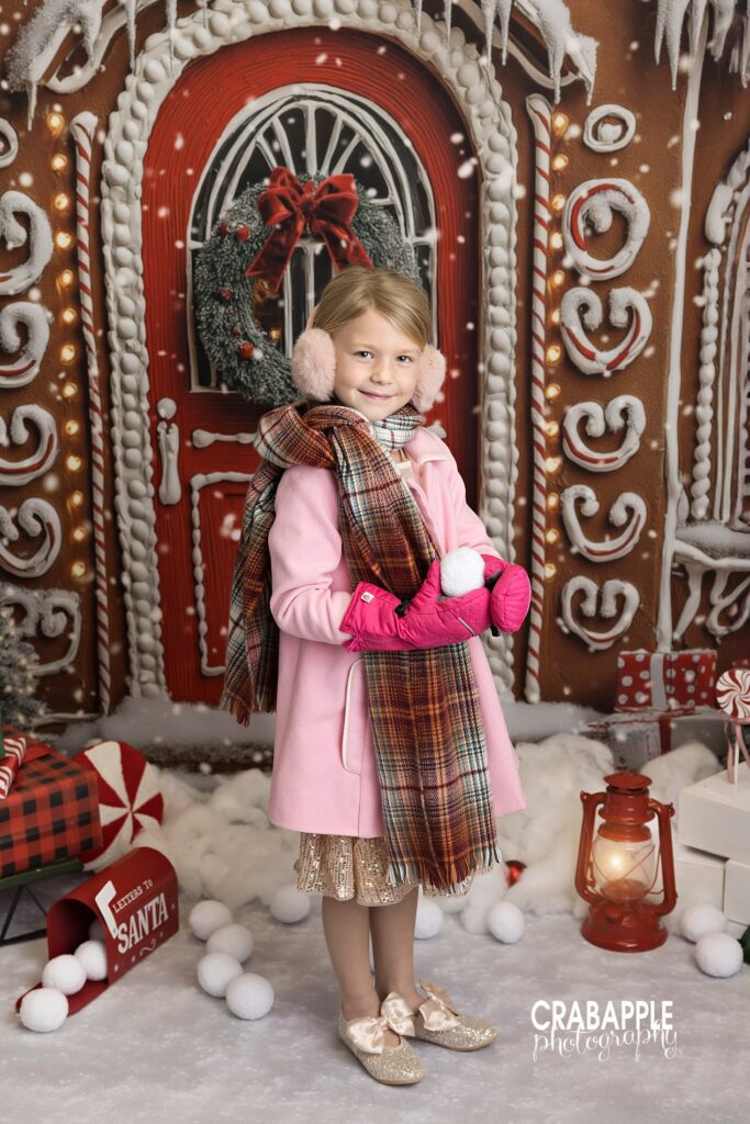 Young girl in winter coat and hat smiling during Christmas photo session
