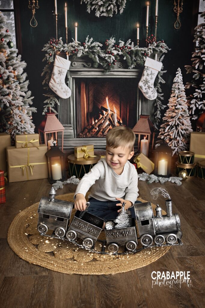 Toddler sitting in toy train surrounded by wrapped Christmas presents.
