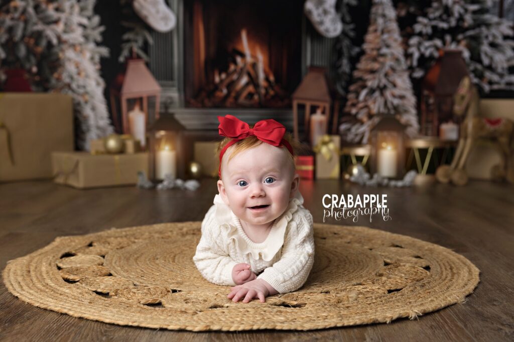 Baby girl doing tummy time smiles at camera during holiday mini session near Boston MA