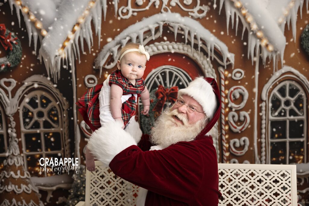 Santa holds baby girl up in the air during holiday mini session near Boston MA