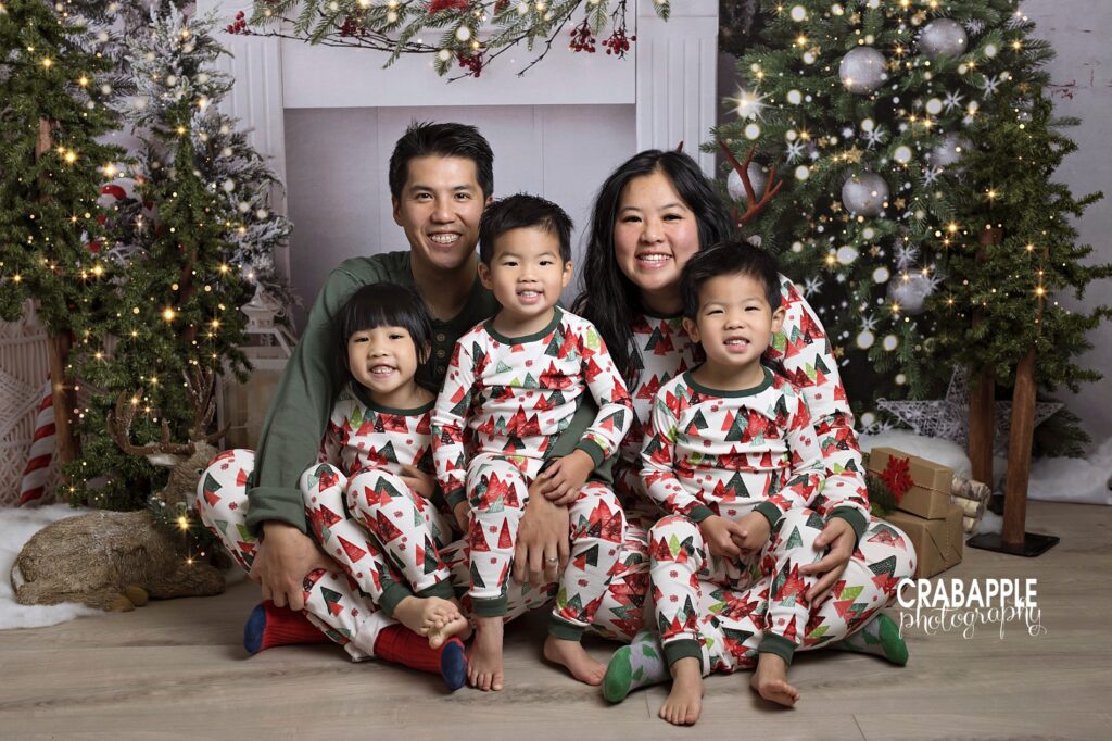 Full family wearing matching festive Christmas tree pajamas during annual Christmas family photos.