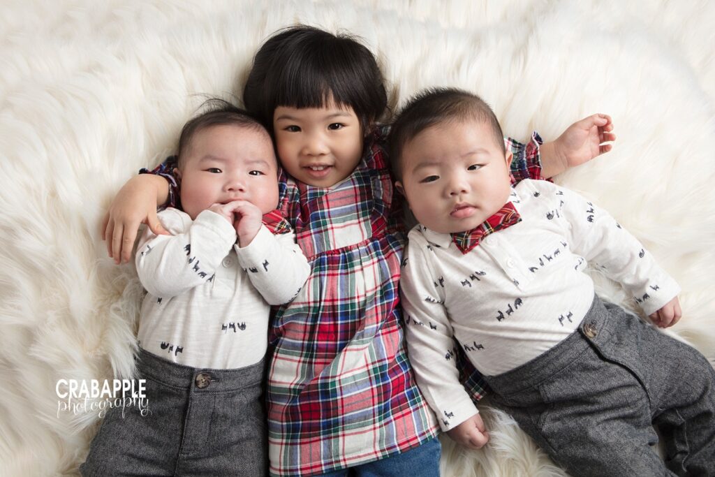 Three siblings dressed in coordinating festive Christmas outfits during holiday portraits.