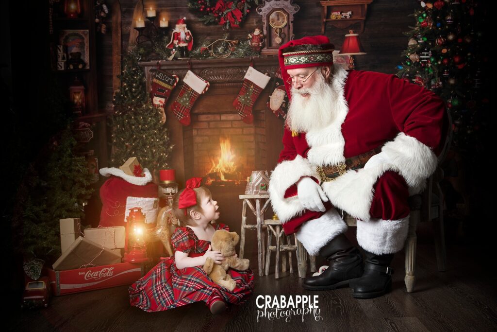 Toddler girl looking up at Santa in a magical holiday composite studio portrait
