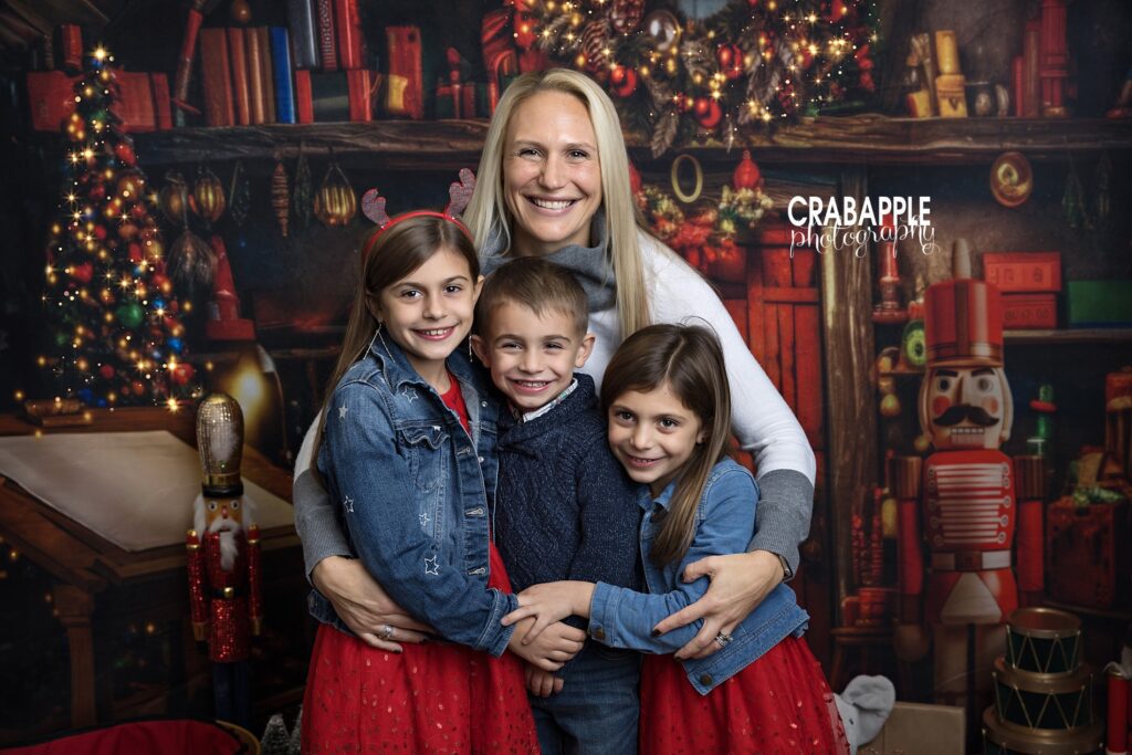 Mom hugging her three children during a cozy holiday studio photo session
