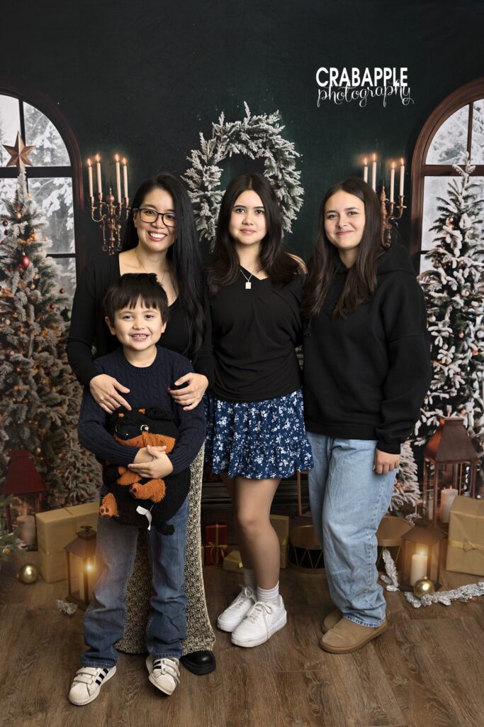 Mom posing with her three children in casual outfits during a holiday studio session
