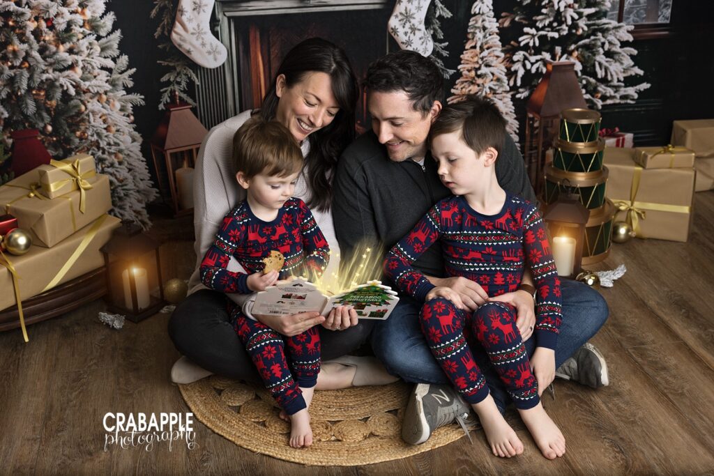 Parents reading a book with their two sons in a cozy holiday studio portrait
