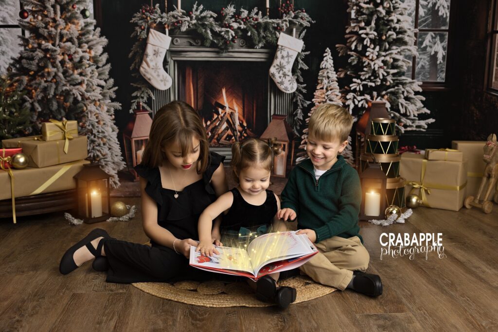 Three siblings reading a Christmas book together in a cozy studio portrait