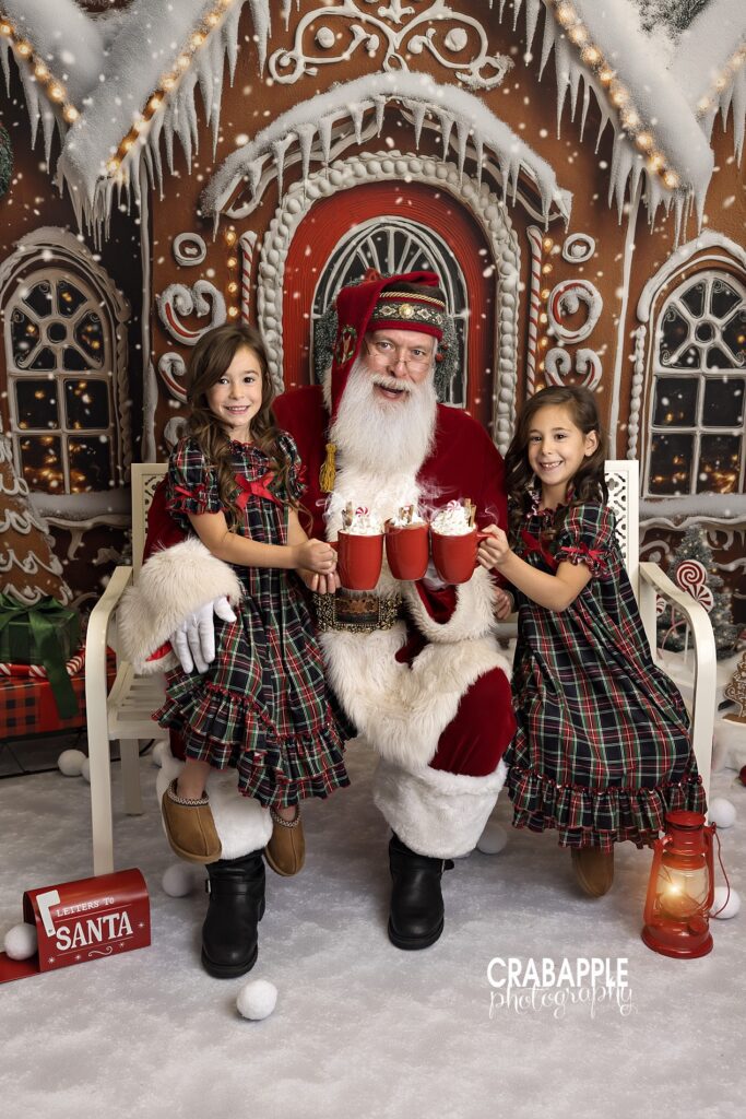 Santa clinks mugs of hot cocoa with two sisters during MA holiday mini session