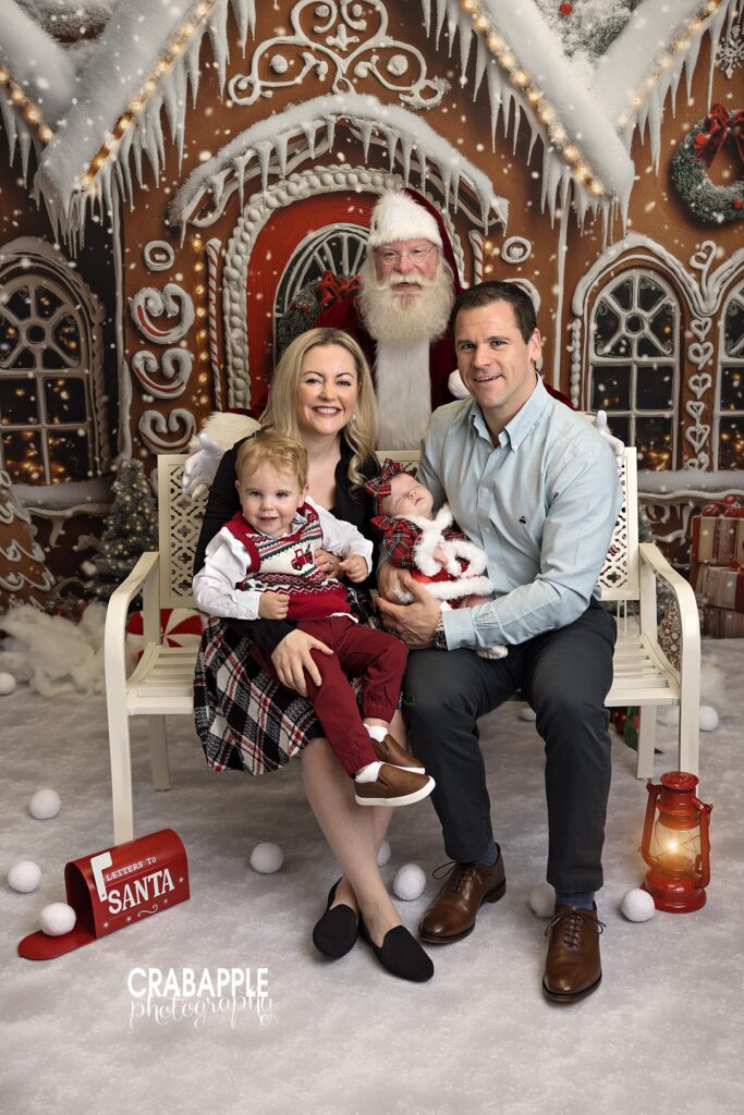 Mom and dad pose with their baby and toddler and Santa Claus during Christmas mini session