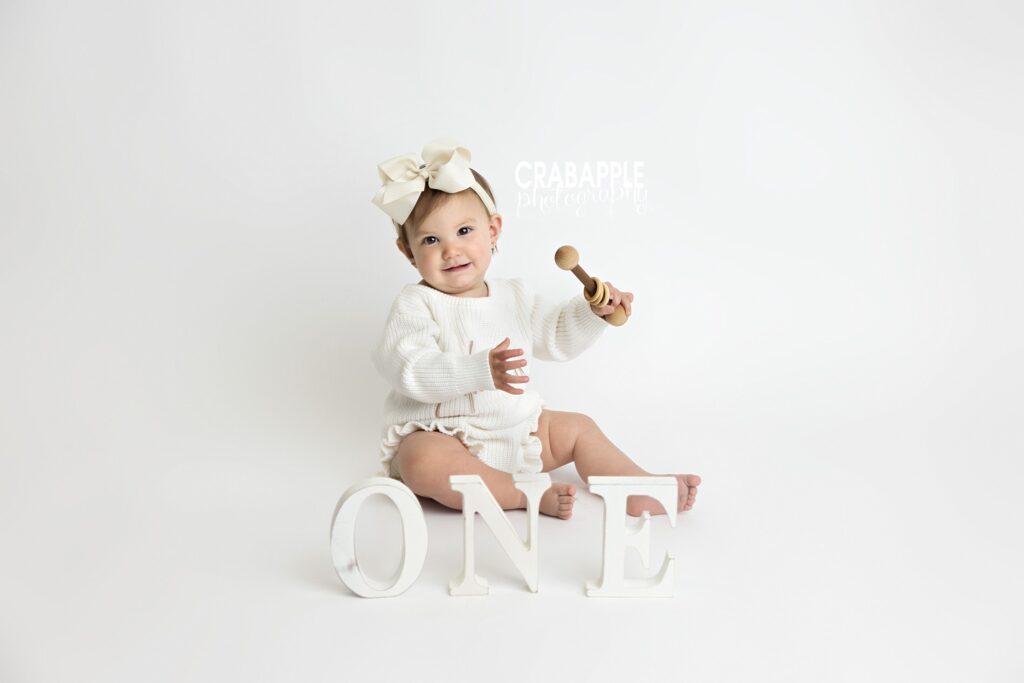 One-year-old girl posing with white letters spelling ONE
