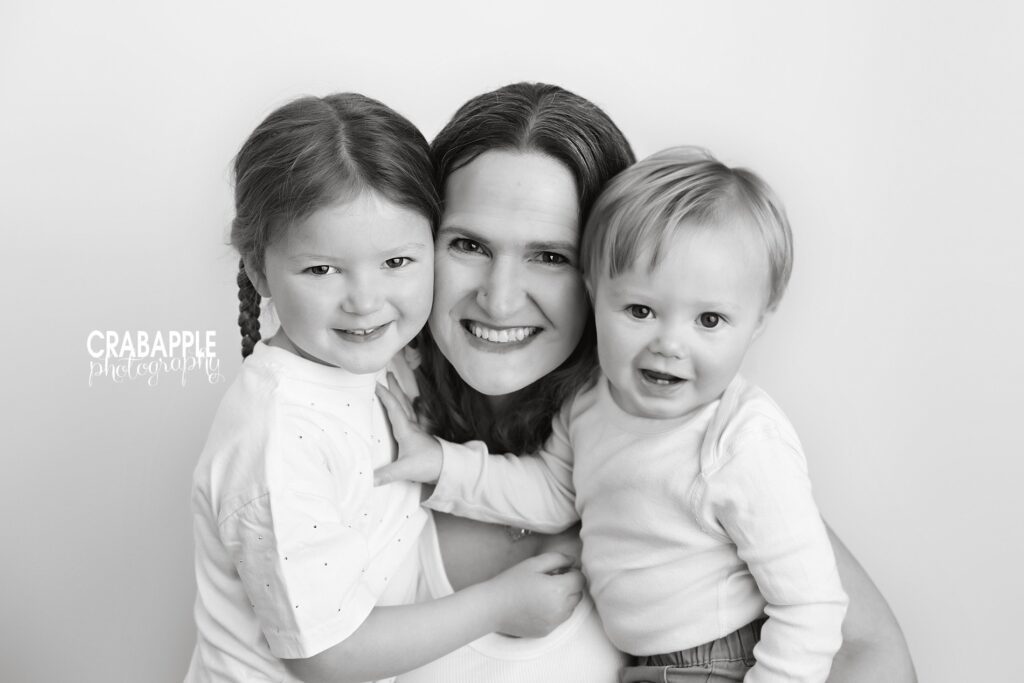 Black and white portrait of mom hugging two toddlers
