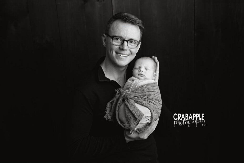 Dad and baby portrait from newborn baby photoshoot Father holding his newborn son during a connection-focused newborn baby photoshoot