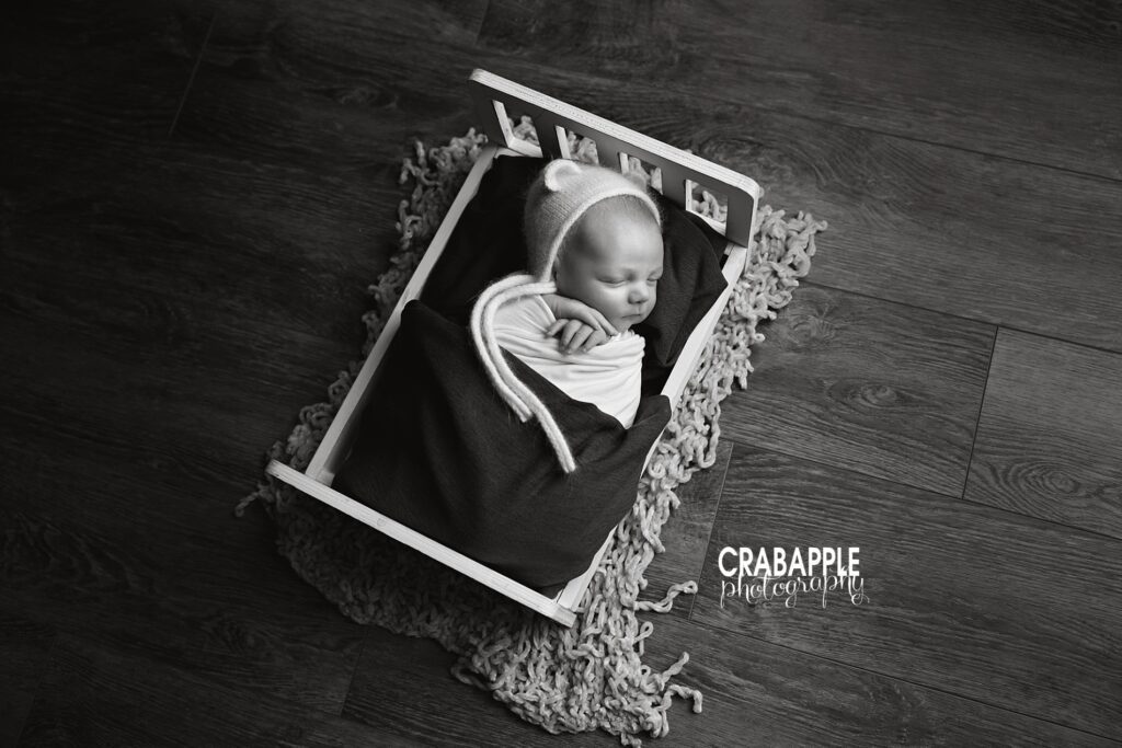 White wooden bed newborn baby photoshoot Newborn posed on a white wooden bed during a newborn baby photoshoot in Andover MA