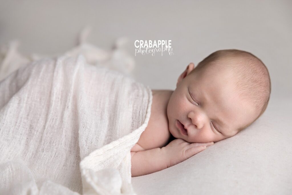 White wrapped newborn baby photoshoot Wrapped newborn baby photographed in white tones during a newborn baby photoshoot