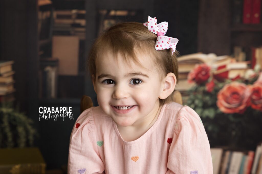 Two year old girl smiling during a Valentine’s Day portrait session in an Andover MA photography studio

