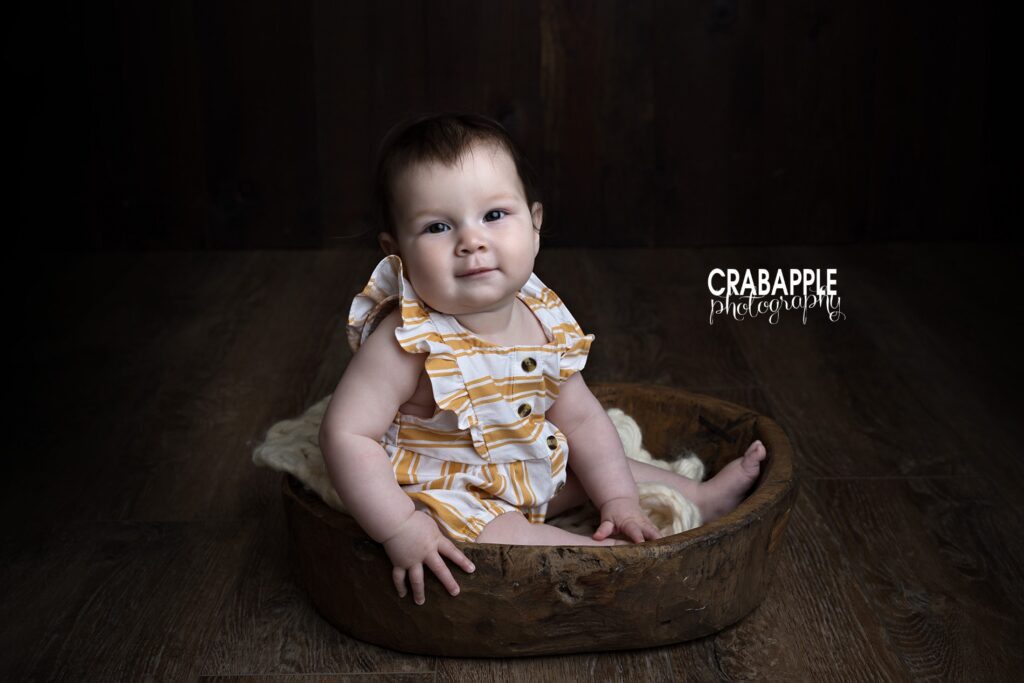 Baby girl pictures documenting a six month sitting milestone in a Newton MA photography studio
with wooden bowl prop