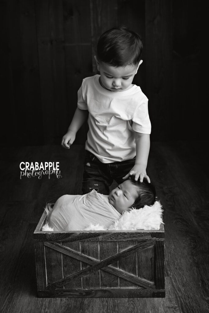 Black and white sentimental candid photo of newborn baby boy and his toddler big brother during Quincy MA newborn photoshoot