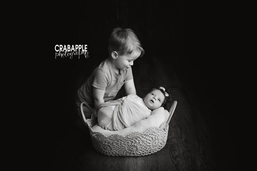 Black and white newborn photography featuring toddler brother gently looking at his newborn sibling in Ipswich MA

